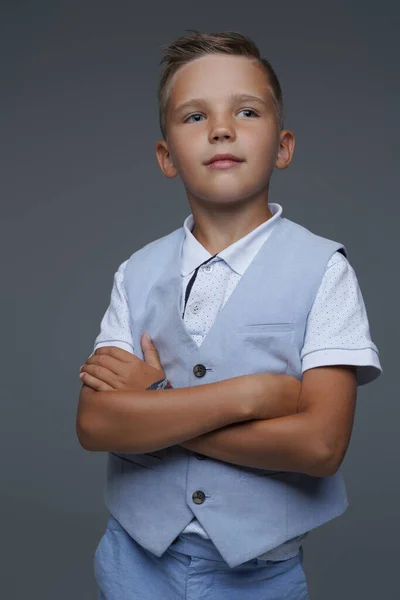 Legal menino vestido no verão traje posando contra cinza fundo — Fotografia de Stock