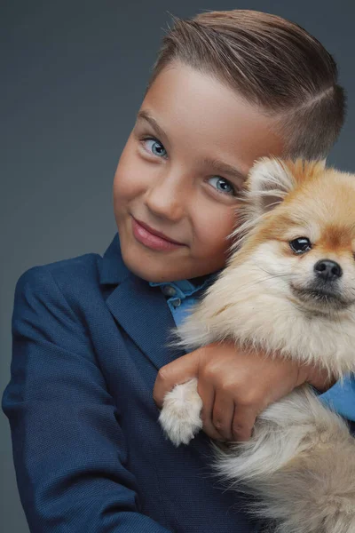 Niño feliz con perrito pequeño sobre fondo gris —  Fotos de Stock