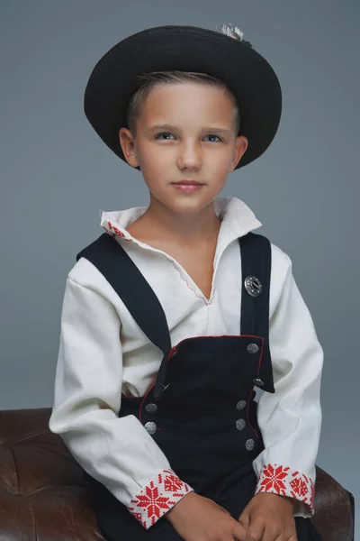 Фотография стильного мальчика в шляпе, сидящего на стуле — стоковое фото