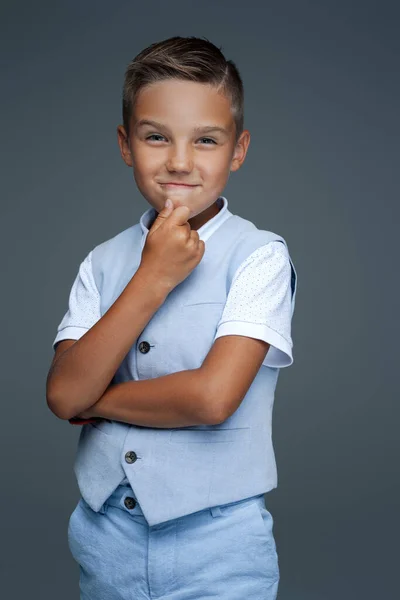 Грайливий дошкільний дитина позує на сірому фоні — стокове фото