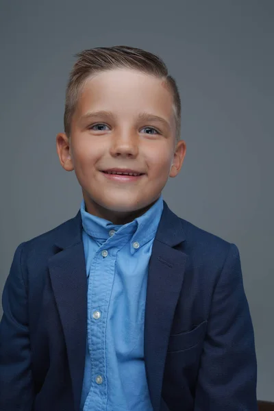 Chico alegre vestido de traje posando sobre fondo gris — Foto de Stock