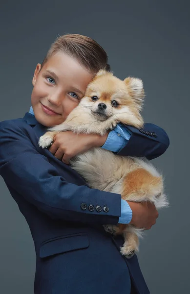 Маленький хлопчик з пухнастим собакою позує на сірому фоні — стокове фото