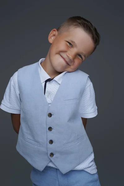 Χαρούμενο και χαριτωμένο αγόρι που ποζάρει σε γκρι φόντο — Φωτογραφία Αρχείου