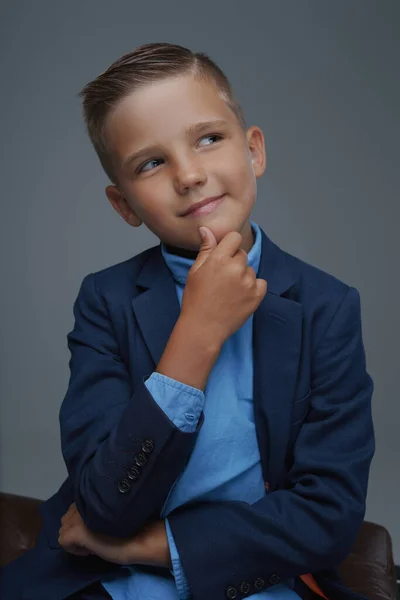 Pensivo menino pré-adolescente vestido de terno contra fundo cinza — Fotografia de Stock