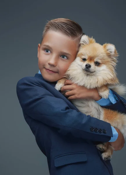 Niño pequeño con perro esponjoso posando sobre fondo gris —  Fotos de Stock