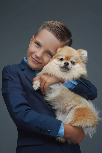 Menino feliz com cachorrinho minúsculo contra fundo cinza — Fotografia de Stock