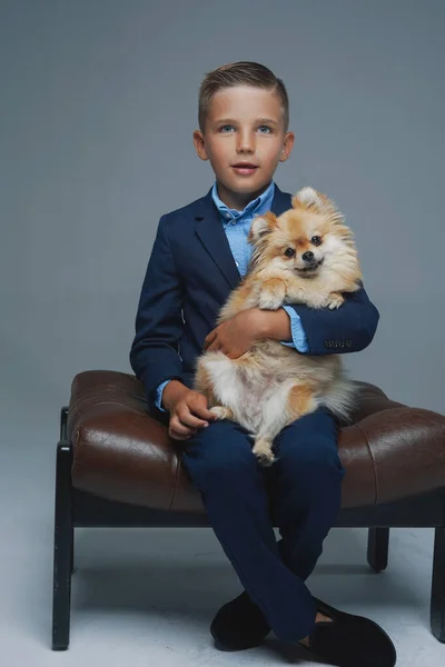 Veselý kluk sedí na židli s pomeranian psem — Stock fotografie