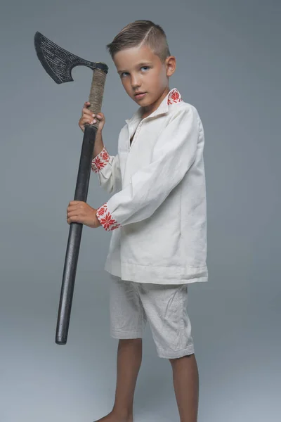 Little boy warrior holding axe against grey background — Stock Photo, Image