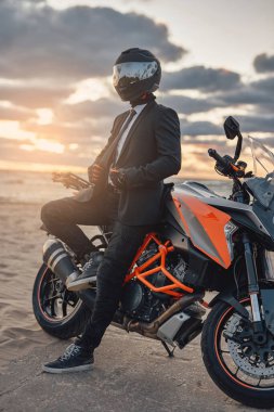 İş adamı motorcu özel motosikletiyle plajda dinleniyor.