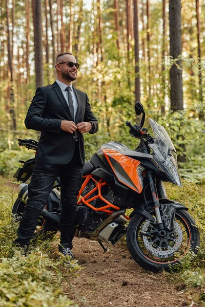 Χαρούμενος άντρας με στολή με σκούρα μοτοσικλέτα στο δάσος — Φωτογραφία Αρχείου