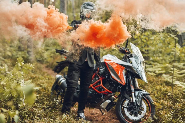 Ormanda elinden renkli dumanlar çıkan bir motosikletçi. — Stok fotoğraf