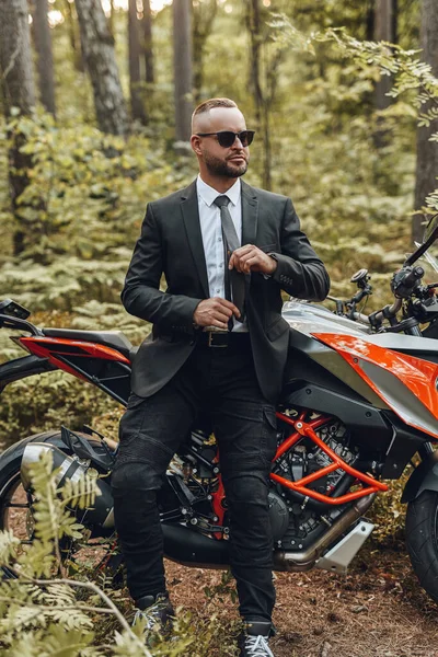 Ormanda havalı bir adam ve siyah kırmızı renkli motosiklet — Stok fotoğraf