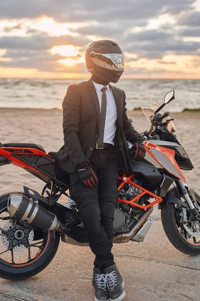 Uomo vestito in tuta e casco in posa sulla spiaggia con bici — Foto Stock