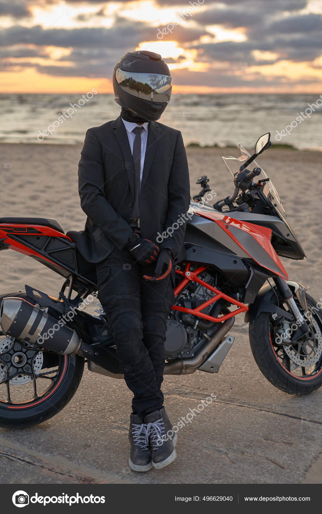 Man dressed in suit and helmet posing on beach with bike — Stock