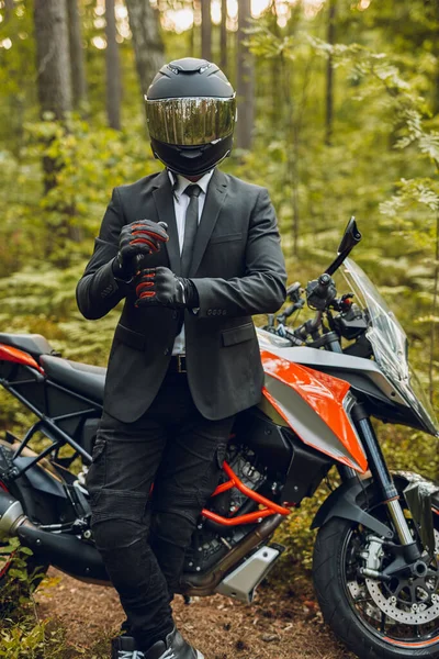 Bello motociclista con casco e moto scura nel bosco — Foto Stock