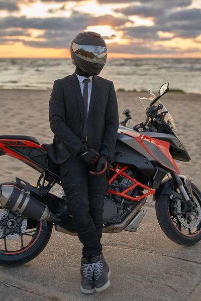 Homem vestido de terno e capacete posando na praia com bicicleta — Fotografia de Stock