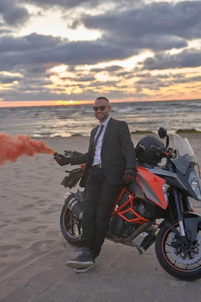 Uomo elegante con bomba fumogena e moto sulla spiaggia — Foto Stock