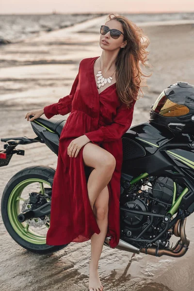 Mulher sensual com moto personalizada preta na praia — Fotografia de Stock