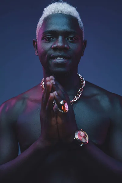 Africano uomo mantenere il suo mani insieme contro scuro sfondo — Foto Stock