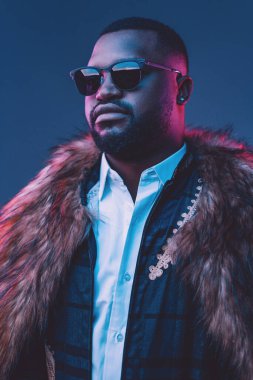 Kürk ve takım elbise giymiş kendinden emin Afrikalı bir adam.