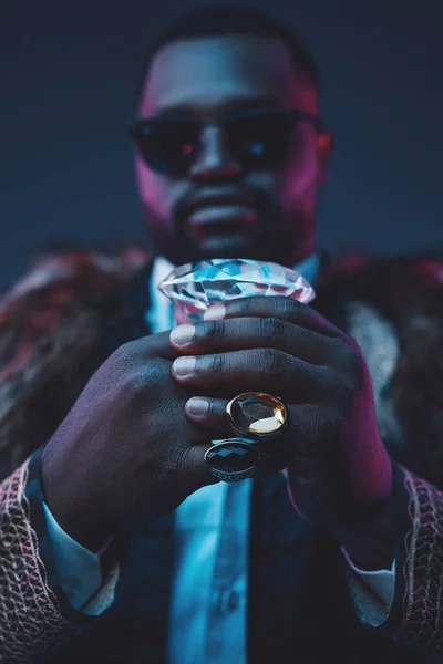 Afrikansk affärsman som håller diamant mot mörk bakgrund — Stockfoto