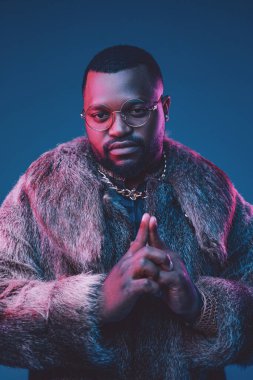 Siyah arka planda lüks kıyafetler giyen Afrikalı bir adam.