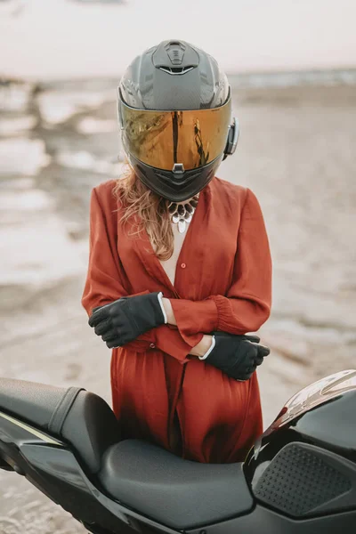 Feminino motociclista com capacete posando em torno de bicicleta na praia — Fotografia de Stock