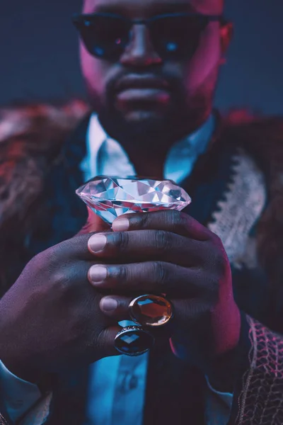 Africano homem de negócios segurando diamante contra fundo escuro — Fotografia de Stock