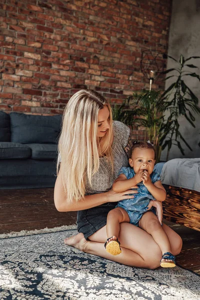 Fürsorgliche Mutter umarmt ihre kleine Tochter im Wohnzimmer — Stockfoto