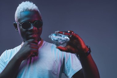 Karanlık arka planda elmas tutan dalgın bir Afrikalı.