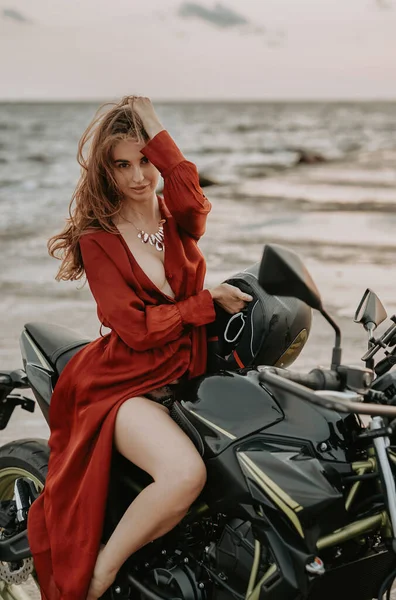 美人バイカー座って上の黒オートバイに対して海 — ストック写真