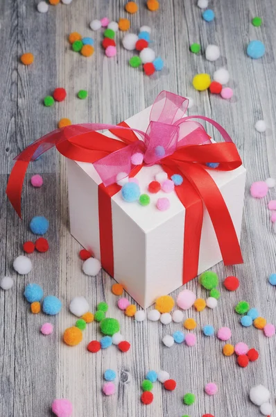 A white box and colorful felt pom poms — Stock Photo, Image