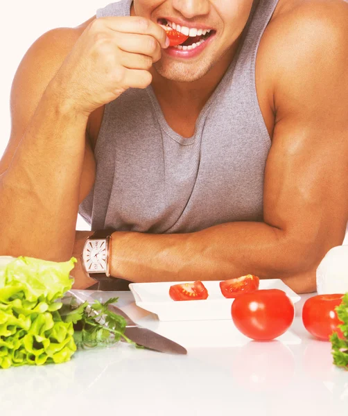 Hombre guapo mordiendo tomate en el estudio —  Fotos de Stock