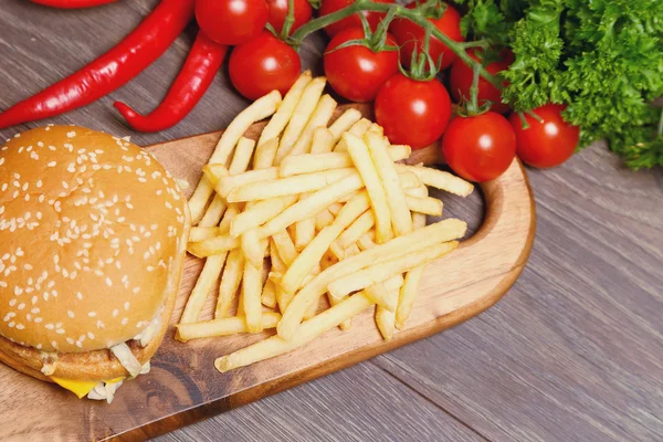 Hamburger and fries on a wooden cutting board — Stock Photo, Image