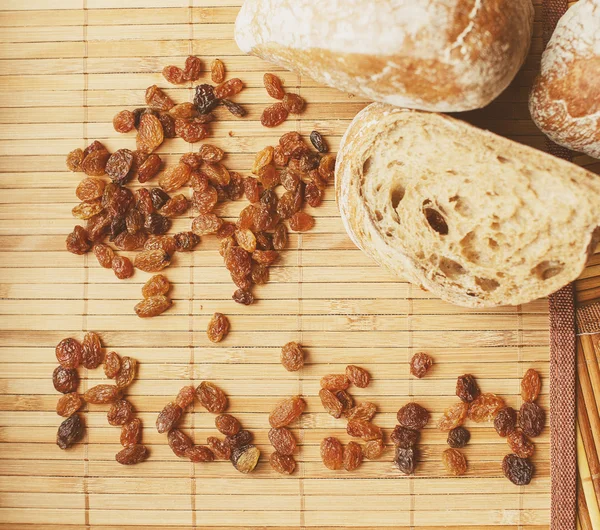 Rozijnen en brood op de houten mat — Stockfoto