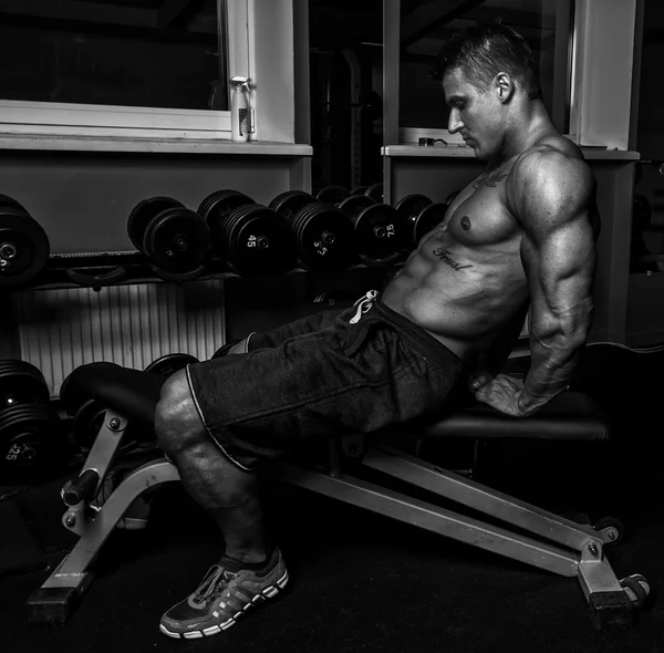 Sexy guy with well looking body isstaring on his abs in gym — Stock Photo, Image