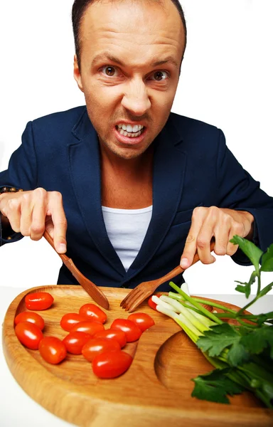A man in a blue blazer trying to cut tomatoes — Stock Photo, Image