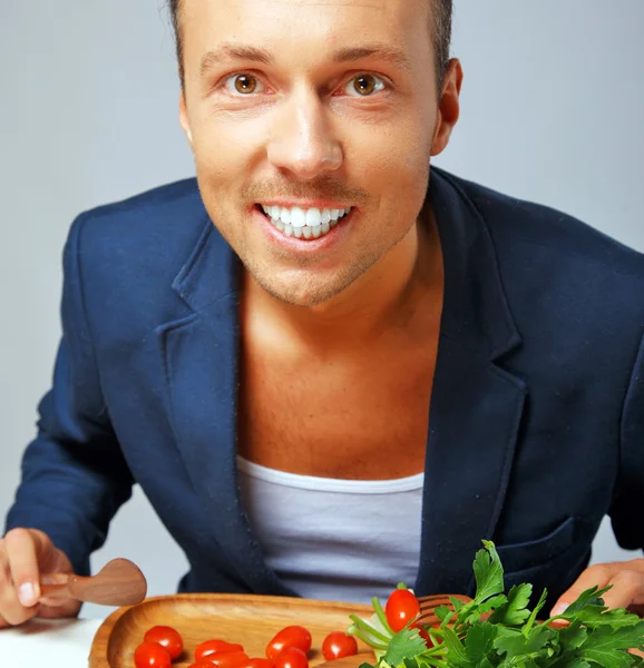 Un hombre en una chaqueta azul feliz de comer verduras —  Fotos de Stock