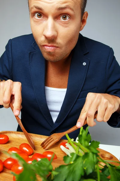 Un hombre en una chaqueta azul comiendo un plato vegetariano —  Fotos de Stock