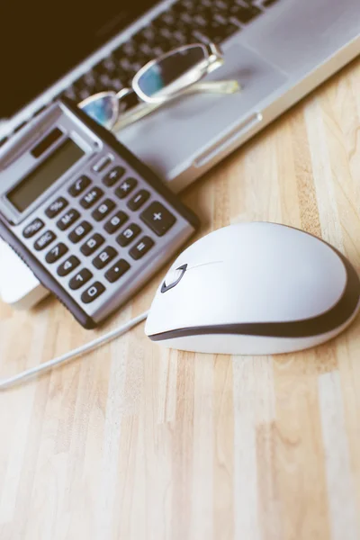 A computer mouse with a calculator, glasses and a laptop