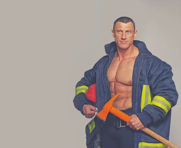 Porträt eines Feuerwehrmanns, der auf grauem Hintergrund posiert — Stockfoto