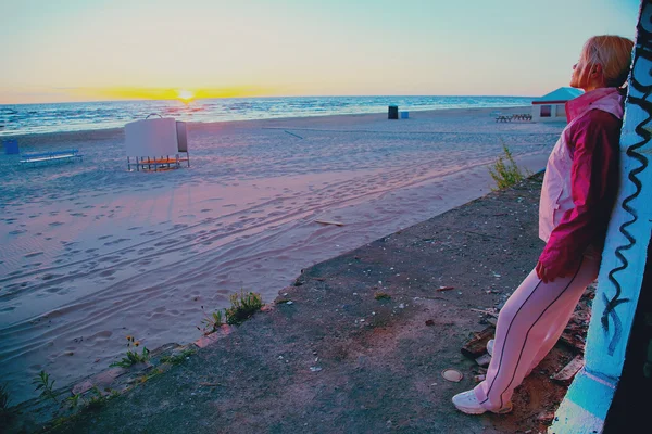 Beautiful girl watching sunset on urban beach — Stock Photo, Image