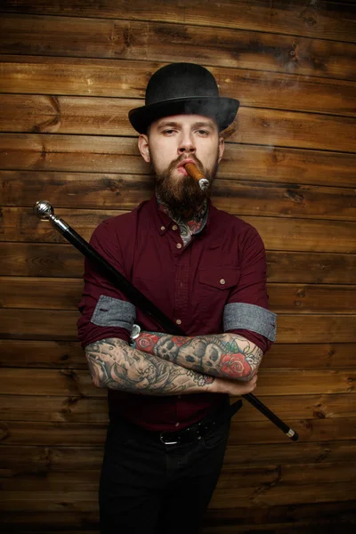 Άνθρωπος με tatto καπνίζει και κατέχει μπαστούνι — Φωτογραφία Αρχείου