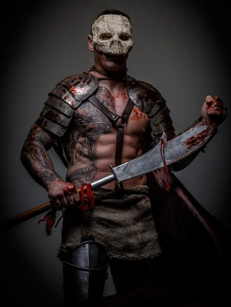 Gladiator in schedel masker houdt zwaard — Stockfoto