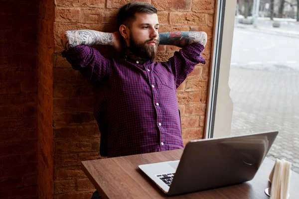 Masculino com tatuagem sentado à mesa — Fotografia de Stock