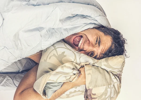 Un hombre cansado en la cama. Él sostiene una almohada —  Fotos de Stock