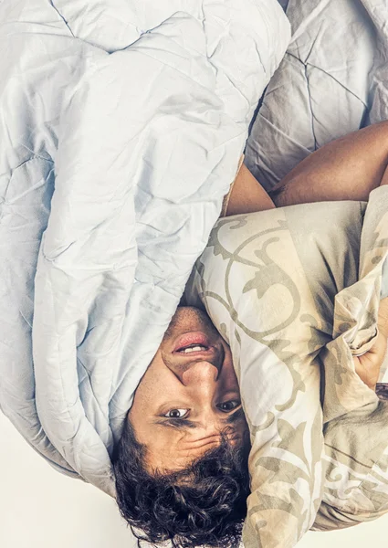 Un hombre cansado en la cama. Él sostiene una almohada — Foto de Stock