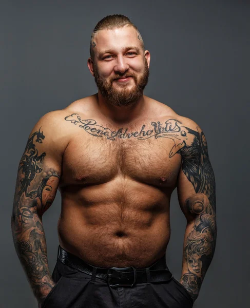 Brutal huge man with tattooes and beard smiling — Stock Photo, Image