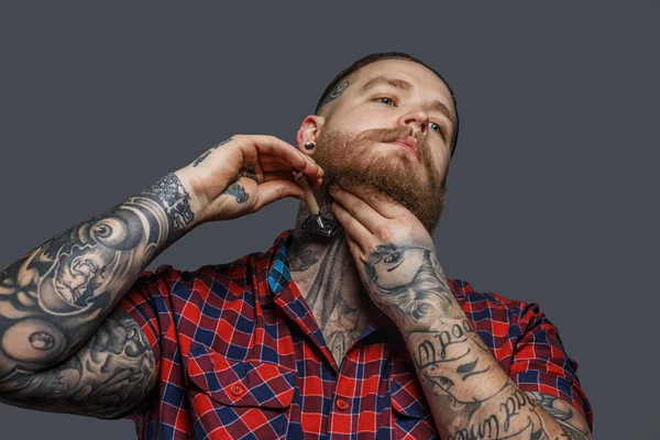 Brutal tattooed male shawing his beard — Stock Photo, Image