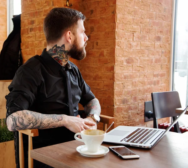 Muž s plnovousem, sedí v obchodě caffee a při pohledu přes vítězství — Stock fotografie